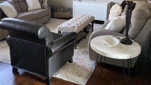 Una sala de estar con sofá, reposapiés, mesa de centro y un televisor de pantalla plana montado en la pared.
