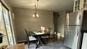 Una cocina moderna con una mesa de comedor, sillas, una araña y un refrigerador de acero inoxidable.