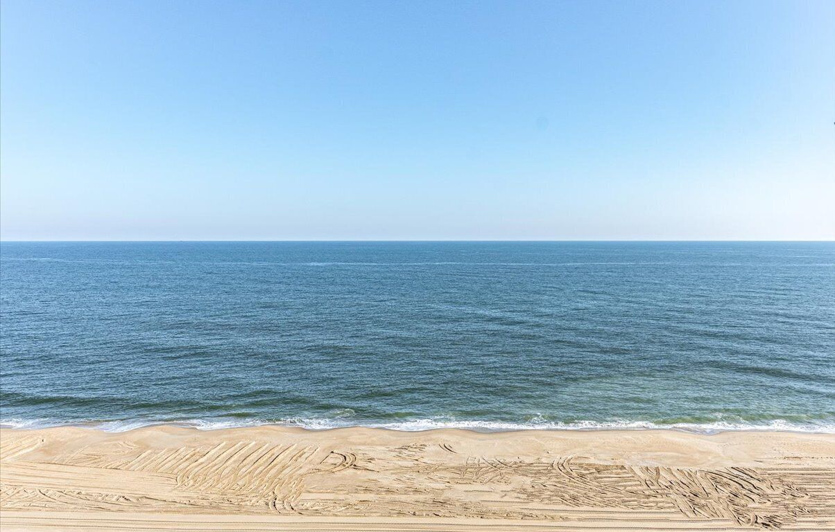 Une plage avec un ciel dégagé et une mer calme.
