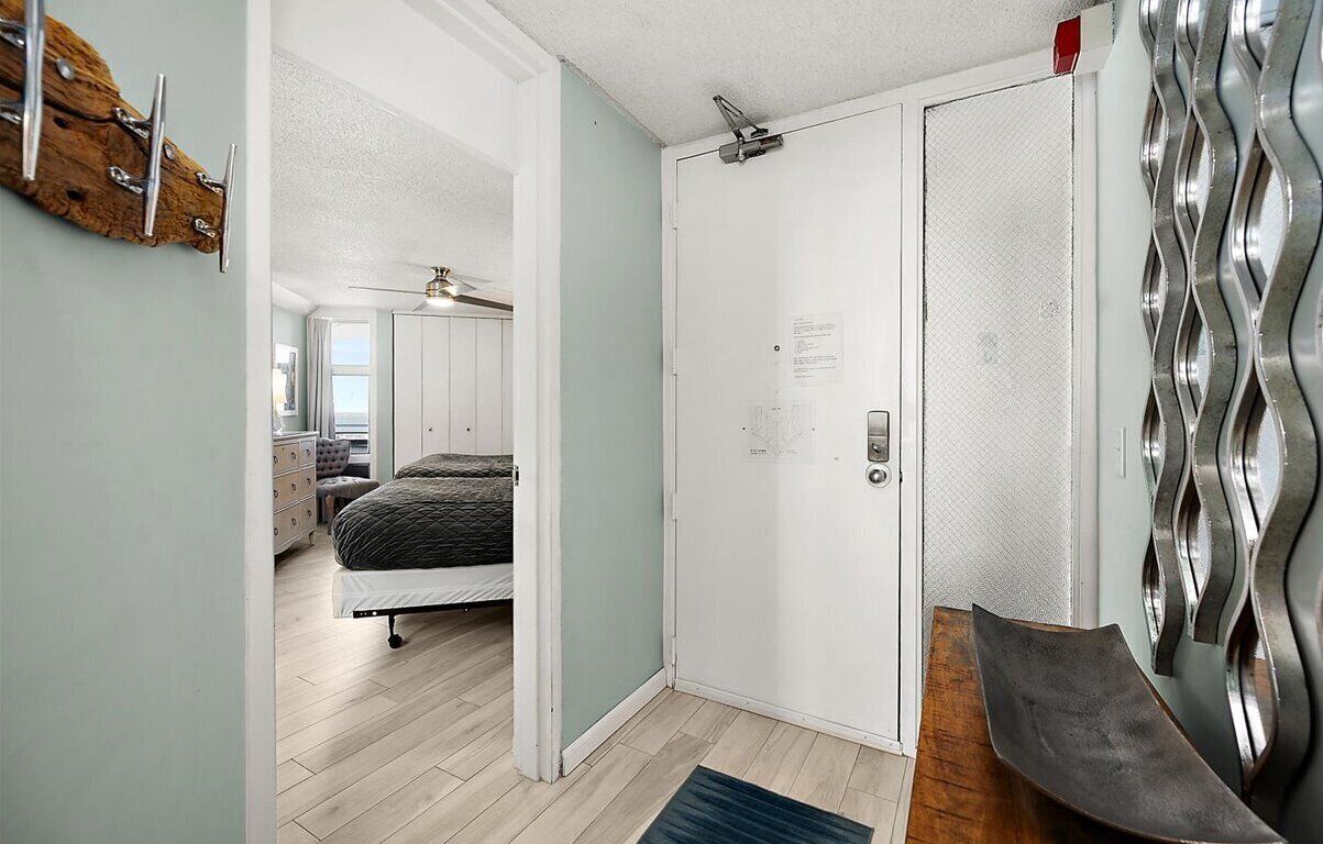 A bedroom with a bed, a dresser, and a door with a metal handle.