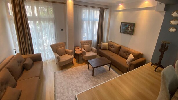 A living room with a sofa set, armchairs, a coffee table, and a dining table. - Beautiful 3-bedroom House With Sea View and Garden (Kusadasi)