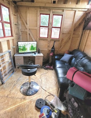A room with a wooden interior, a leather sofa, a television, and a desk with a computer. - 2-bed Apartment, Sleeps 4,on-site Parking (Manchester)