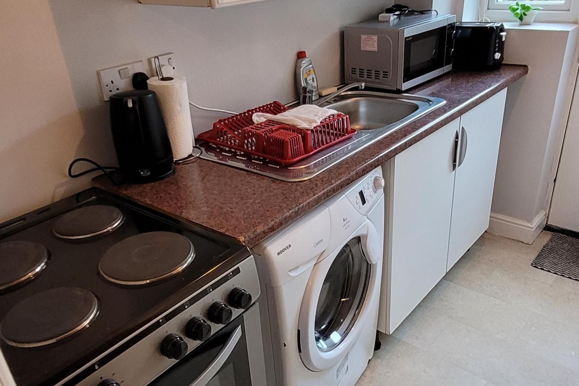 A compact kitchen with a stove, microwave, and washing machine.