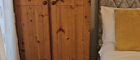 Ein Schlafzimmer mit einem Holzschrank, einem Bett mit Kopfteil und einem gelben Teppich.