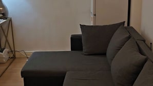 Una sala de estar moderna con un sofá seccional, una mesita auxiliar, una lámpara y un control remoto sobre el sofá.