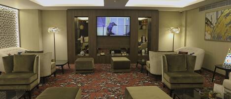 Una sala de estar moderna con sofás, otomanas, un televisor de pantalla plana y lámparas decorativas.