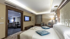 A hotel room with a large bed, a desk, a chair, and a television. - Az Hotels Grand Oran (Es Senia)