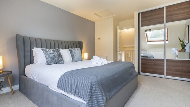 A modern bedroom with a large bed, a bedside table, a mirror, and a sliding door leading to a bathroom. - Fab Tree-Lined, Upmarket Area | Next to Queens Uni - Pass the Keys (Belfast)