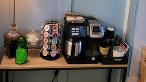 En kaffestation med en skylt som lyder: ”KAFFE ÄR ALLTID EN BRA IDÉ”, en kaffebryggare, en lampa och olika typer av kaffebehållare.