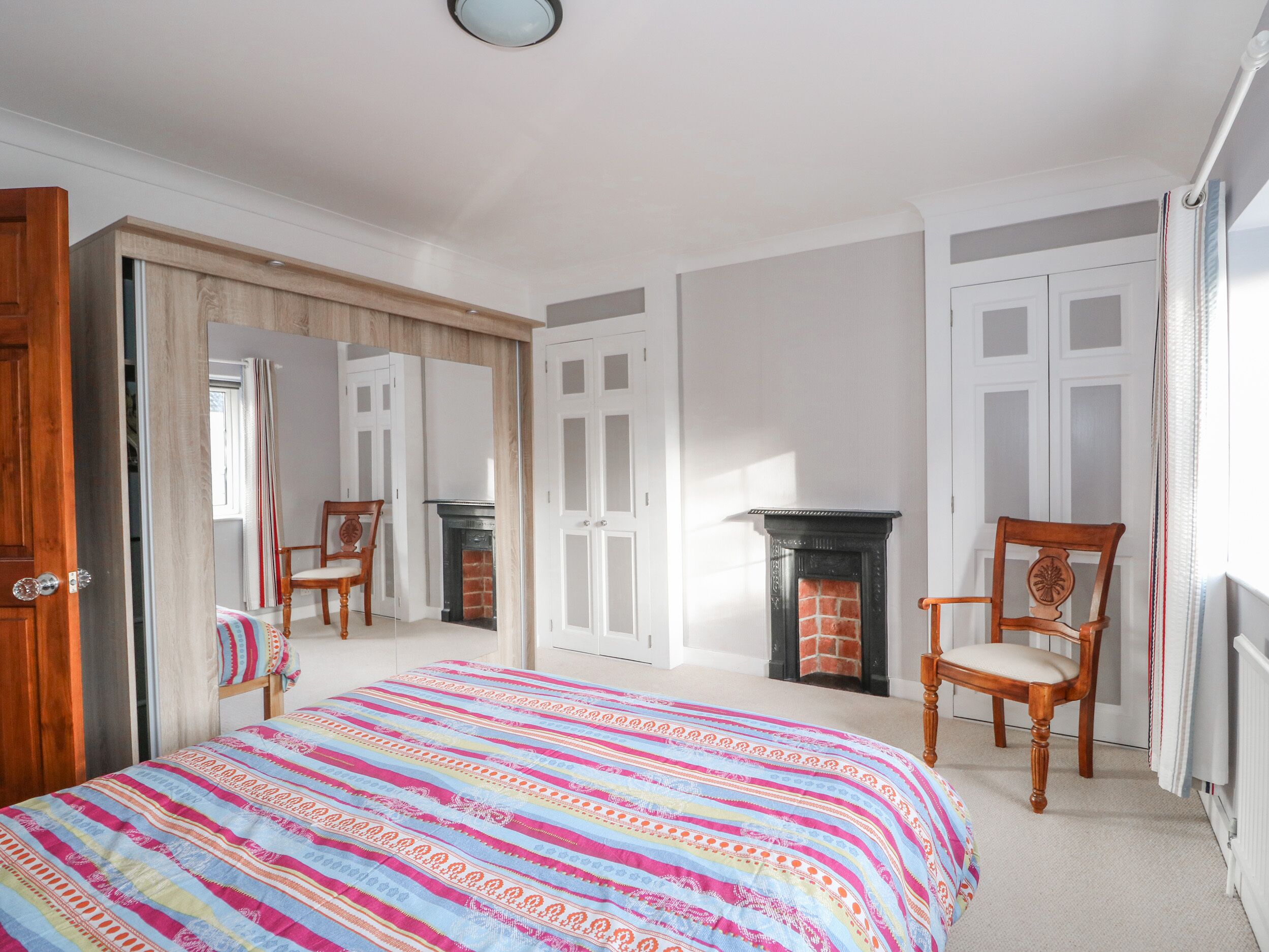 A bedroom with a bed, a fireplace, and a mirror.