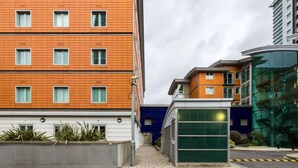 A modern building with a brick facade, multiple windows, and a small green structure. - The Waterloo Flats (London)