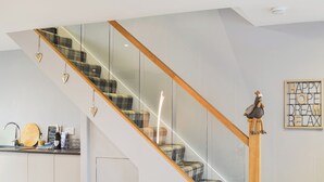 Eine moderne Küche mit einer Glaskonstruktion als Treppe, einem Holzgeländer und einem dekorativen Hahn.