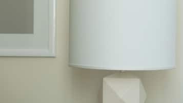 A modern lamp with a geometric base and a white lampshade on a wall.