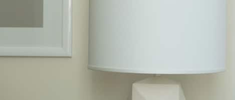 A modern lamp with a geometric base and a white lampshade on a wall.