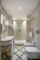 A modern bathroom with a glass-enclosed shower, a sink with a mirror, and a toilet.