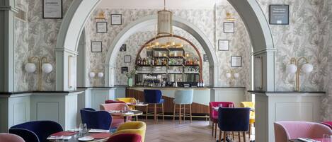 Un restaurante con barra central, varias opciones de asientos y menús enmarcados en las paredes.