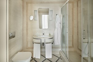 A modern bathroom with a glass shower enclosure, a white sink with a mirror above, and a toilet.