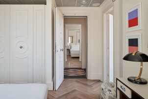 A hotel corridor with a bed, a desk, and a lamp.