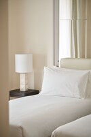 A hotel room with a bed, a nightstand with a lamp, and a window with curtains.