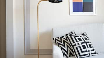 Un soggiorno moderno con una lampada da terra, un divano con cuscini decorati e un quadro astratto incorniciato appeso al muro.