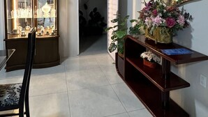 Una habitación con un aparador de vidrio, una silla, una consola con espejo y una planta en maceta.