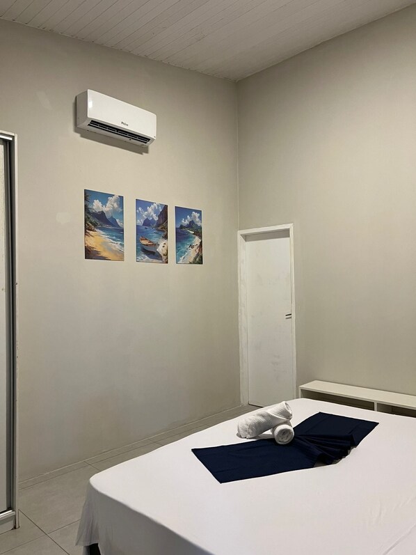 A bedroom with a bed, a door, and three paintings on the wall.