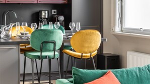 A modern kitchen with a dining area, featuring a bar stool, a sofa, and a window with a view. - ARNEM - cosy T3 - Two Bedroom Apartment, Sleeps 4 (Rennes)
