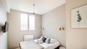 A bedroom with a bed, a radiator, a window, a wall-mounted lamp, and a framed botanical print. - ARNEM - cosy T3 - Two Bedroom Apartment, Sleeps 4 (Rennes)