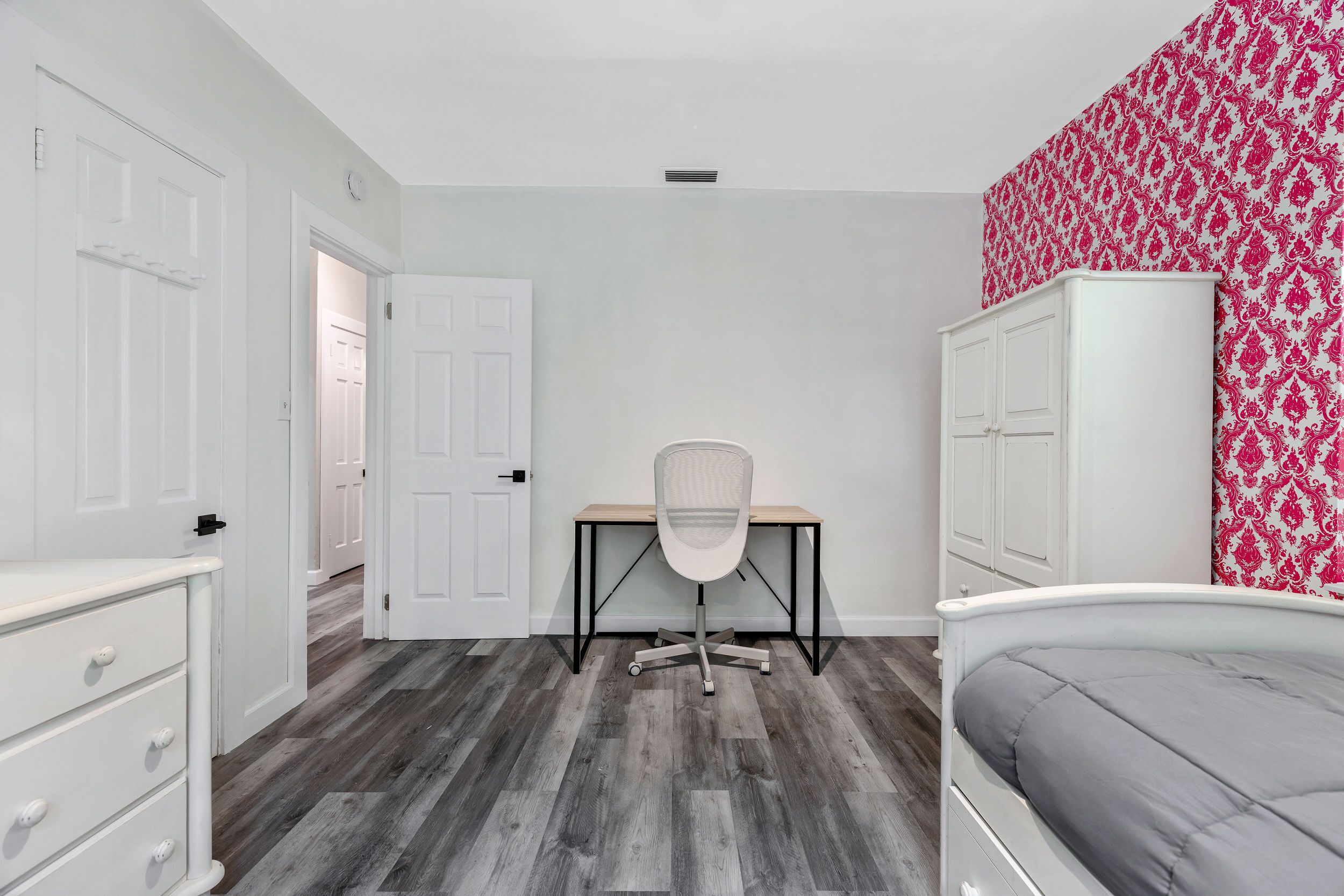 Une chambre à coucher comprenant un lit, un bureau, une chaise et une armoire.