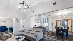 A spacious living room with a gray sectional sofa, a round coffee table, and a dining area with a table set for four.