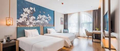 A hotel room with two beds, a desk, a chair, a TV, and a large floral painting on the wall.