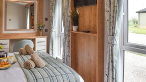 A bedroom with a bed, a dresser, a mirror, a TV, and a window with curtains. - 2 bedroom accommodation in Barrow, near Clitheroe (Barrow, near Clitheroe)