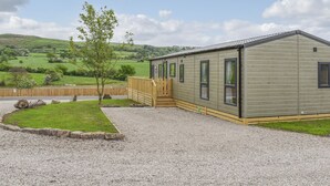 A single-story mobile home with a gravel driveway and a wooden fence. - 2 bedroom accommodation in Barrow, near Clitheroe (Barrow, near Clitheroe)