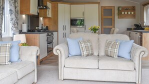 A cozy living room with a sofa, a coffee table, and a TV. There is a kitchen area with cabinets and appliances. - 2 bedroom accommodation in Barrow, near Clitheroe (Barrow, near Clitheroe)