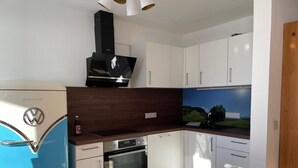Une cuisine moderne avec des meubles blancs, un four encastré, une cuisinière et une hotte noire.