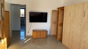 Une pièce comprenant une grande armoire en bois, un téléviseur à écran plat fixé au mur et un banc.