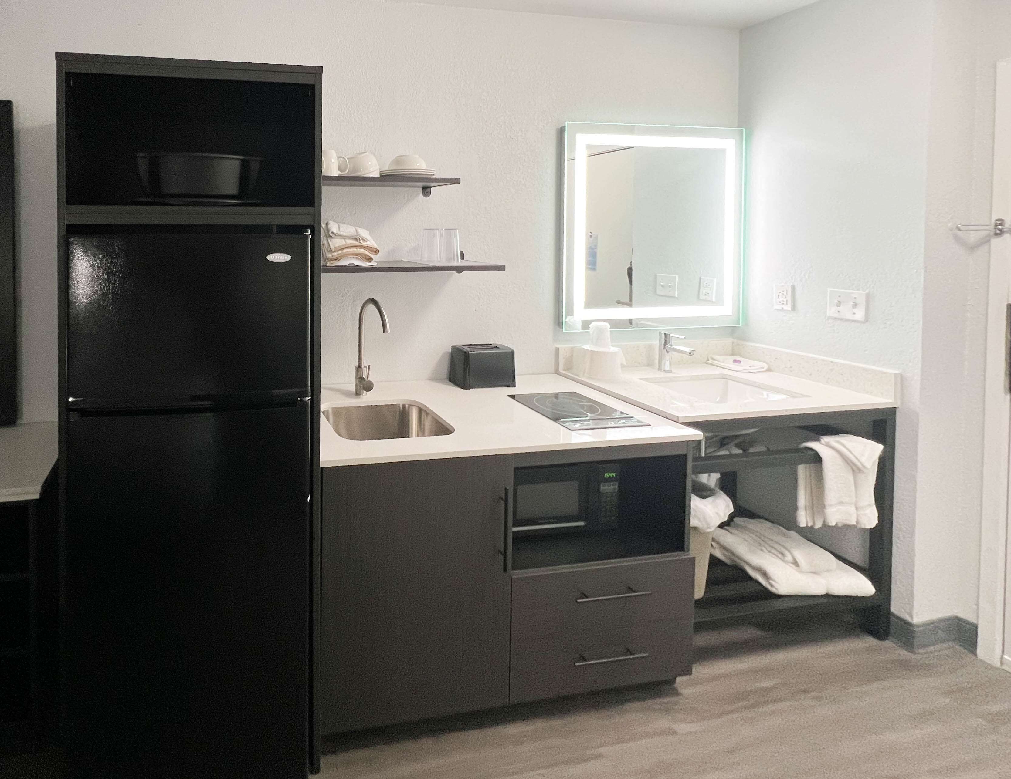 A compact kitchen with a refrigerator, sink, and a mirror above the countertop.