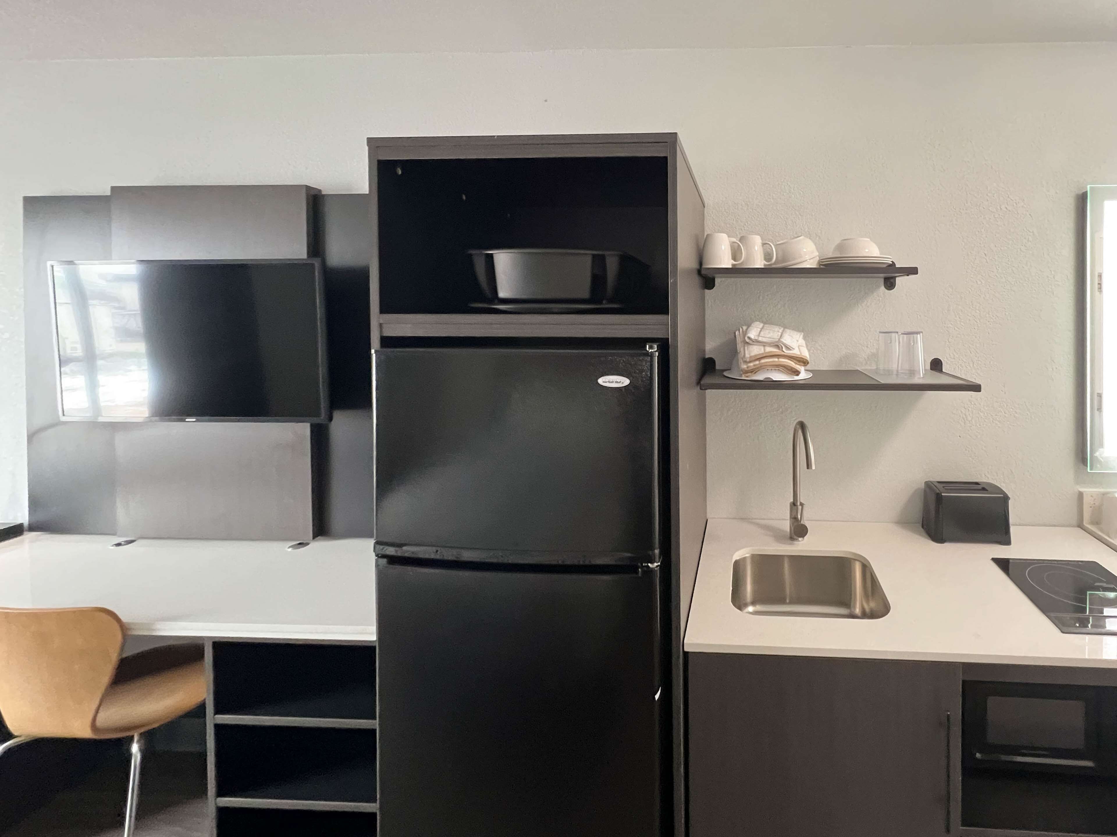 A modern kitchen with a black refrigerator, a sink, a toaster, and a microwave.