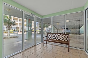 A hotel lobby with a bench, large glass doors, and a view of the street outside.