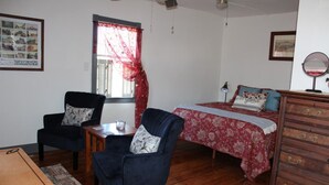 Una habitación con cama, silla, mesa y cómoda.