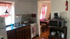 Una cocina compacta con armarios de madera, estufa a gas, fregadero, microondas y cafetera.