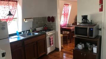 Une cuisine compacte dotée de meubles en bois, d’une cuisinière à gaz, d’un évier, d’un four à micro-ondes et d’une machine à café.