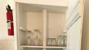 Una cocina con armarios blancos, cafetera y extintor.