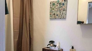 Un baño con inodoro, lavamanos, espejo, cortina de ducha y un adorno de pared.