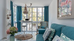 A modern living room with a teal sofa, a glass coffee table, and a laptop on a white stand. - Pto. Banús, modern, bright, 2-bedroom Apart., pool (Puerto Banús)