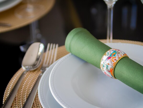 A neatly set dining table with a green napkin ring, a white plate, and silverware.
