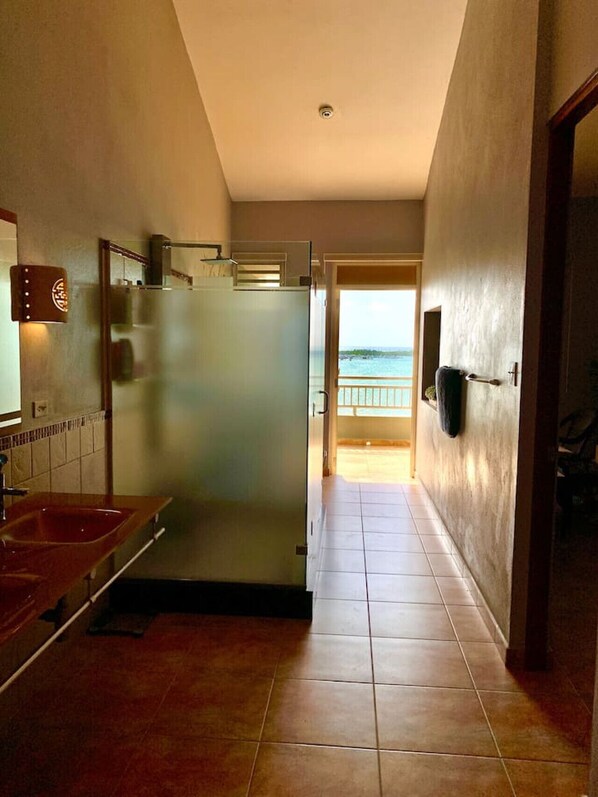 A hallway with a kitchen area, a refrigerator, and a view of the sea through an open door.