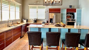 A modern kitchen with a central island, bar stools, and built-in appliances. - Oceanfront Casa Vista Fajardo (Fajardo)