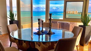 A round glass table with chairs in a room with large windows overlooking the ocean. - Oceanfront Casa Vista Fajardo (Fajardo)