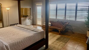 A bedroom with a four-poster bed, a fan, and a view of the sea through large windows. - Oceanfront Casa Vista Fajardo (Fajardo)